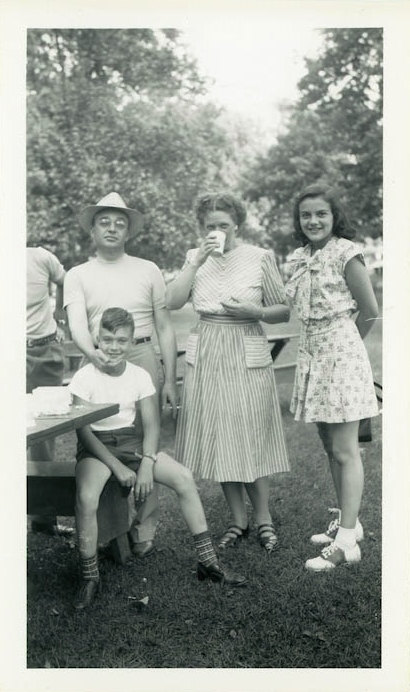 vintage 1940s image of family at a park having a picnic in 1940s early 1950s fashions. 