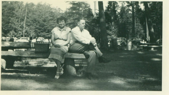 1940s / 1950s vintage photo of a couple sitting on a picnic table having a picnic. 