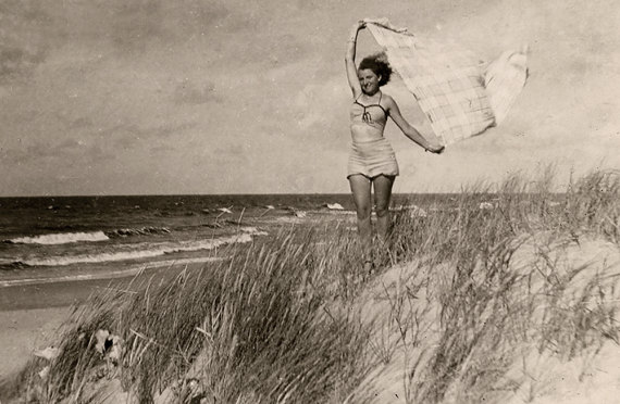 1940s summer photo of young woman in swimsuit posing by the lake.