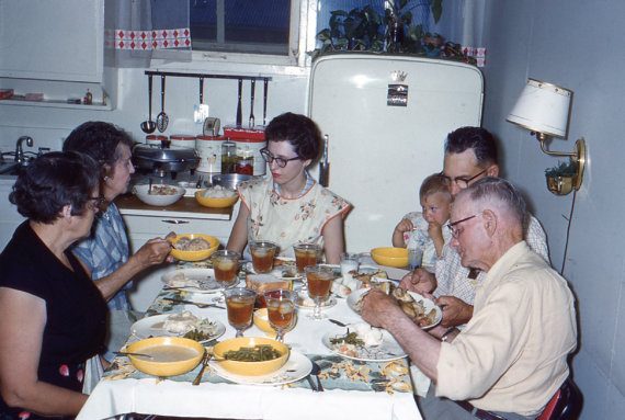 1950s vintage photo of a family eating dinner in their kitchen at the table. Super 1950s kitchen decor / interior design inspiration.