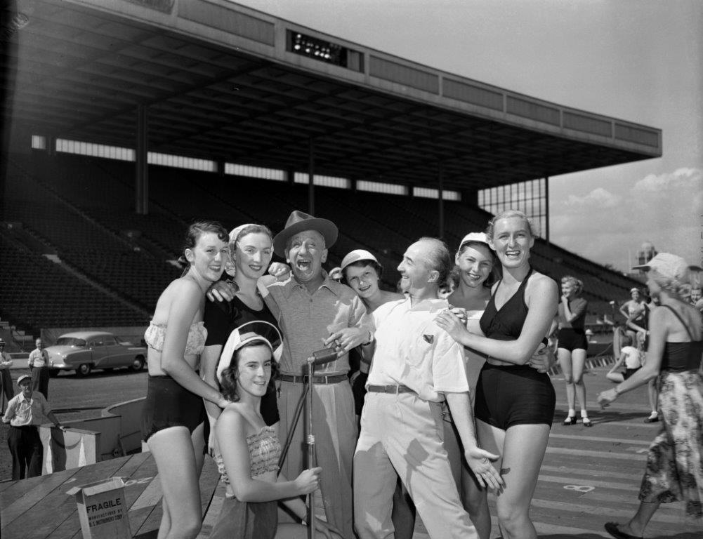 Jimmy Durante and young women in 1951 pose together in 1950s swimsuits and summer outfits.