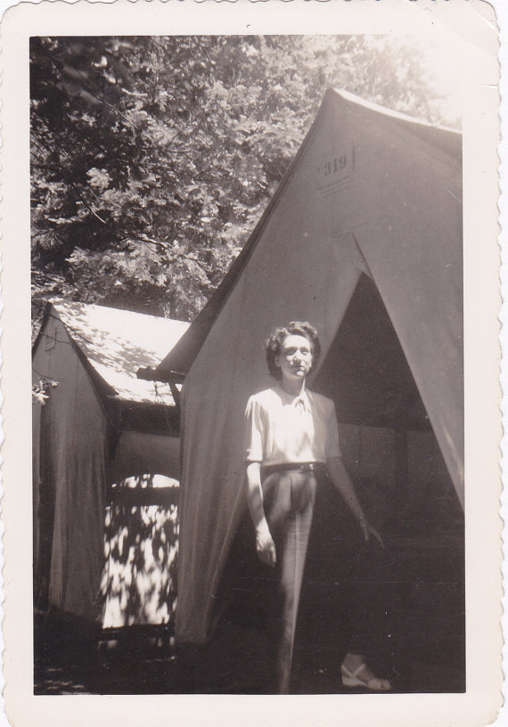 1940s vintage photo of a woman in 1940s pants and blouse posing outside of a tent. Vintage camping photo.