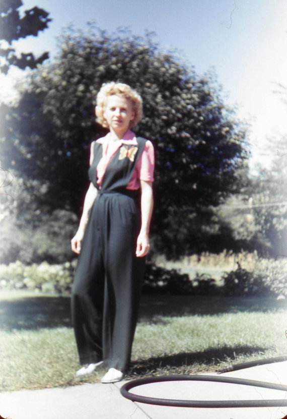 1940s vintage photo of a young woman in a one piece jumpsuit with a giant butterfly brooch or design on the chest area. Super 1940s fashion.