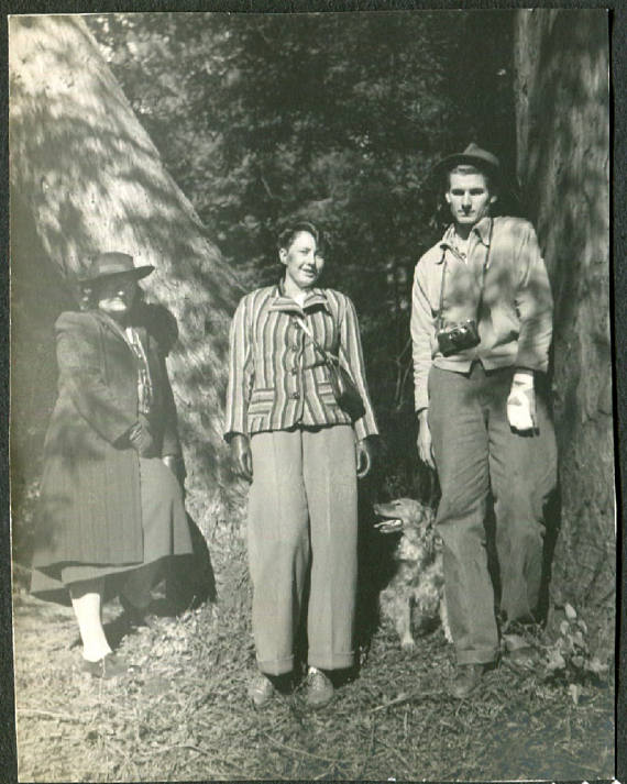 1940s vintage photo of 2 women and man posing in the woods in 1940s fashions. 