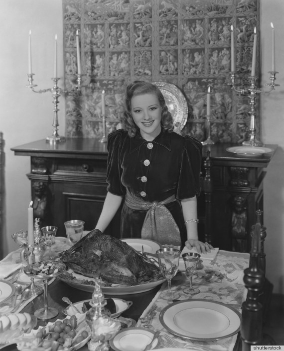 1940s vintage photo of a 1940s movie star posing in front of her turkey table at thanksgiving. 