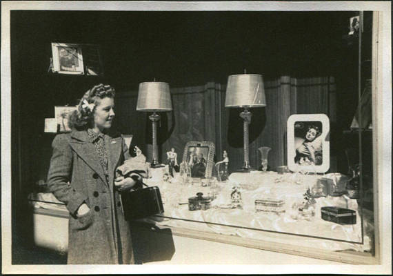 1940s vintage photo of a young woman with 1940s hairstyle looking at window display. 