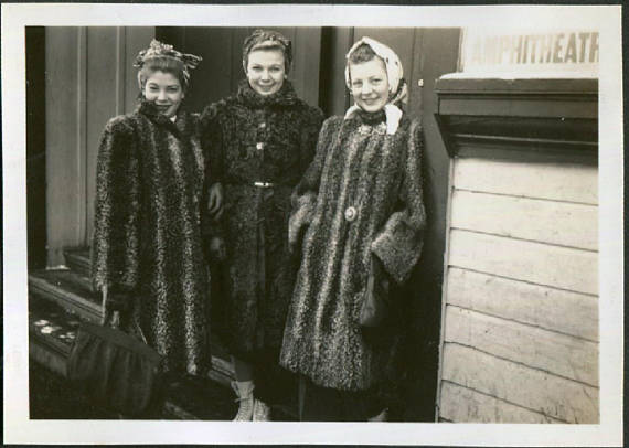 1940s vintage photo of 3 woman in fur coats and wearing hair scarfs psoing together for a photo. 