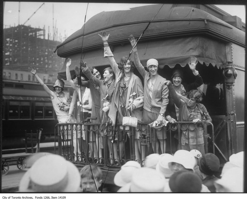 1920s vintage photo of the 1928 Canadian women heading to Summer Olympics waving from the back of a train in 1920s fashions. 