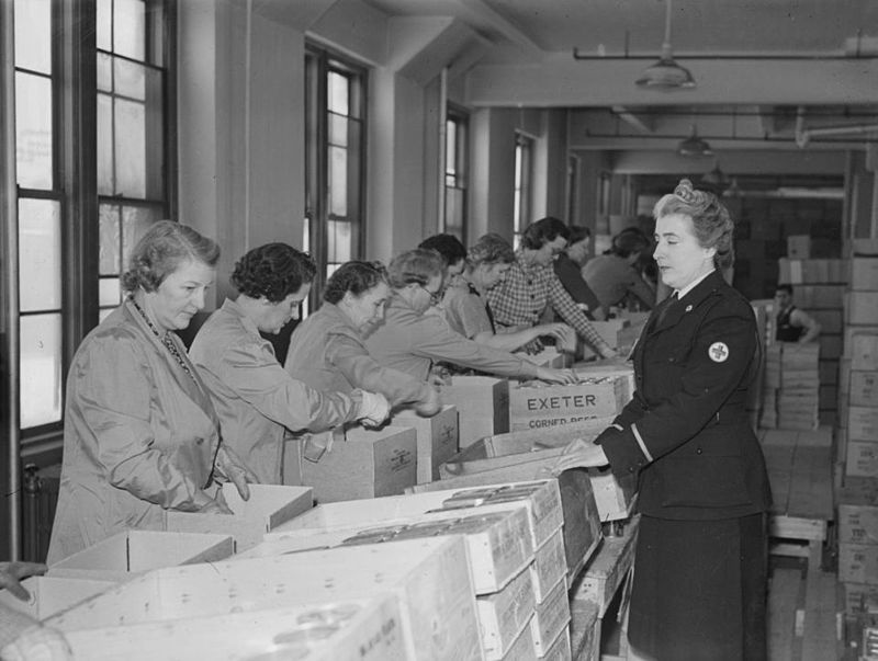 1940s vintage photo of Canadian Women volunteers from Canadian Red Cross assemble packages for prisoners of war in 1942.