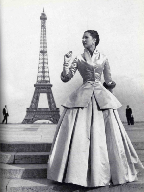 Dior New Look vintage modeling image of a woman posing in front of the Eiffel Tower in a two piece Dior Outfit. 