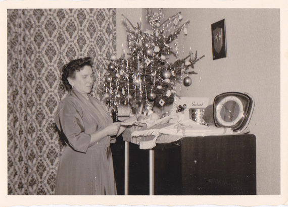 Corner Christmas Tree- 1950s Vintage Photograph of a woman in a 1950s dress decorating the mantel with gifts received. 