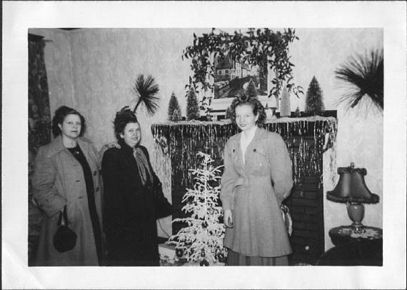 1940s Vintage Photo of a Women Standing By Small Christmas Tree in their 1940s coats. 