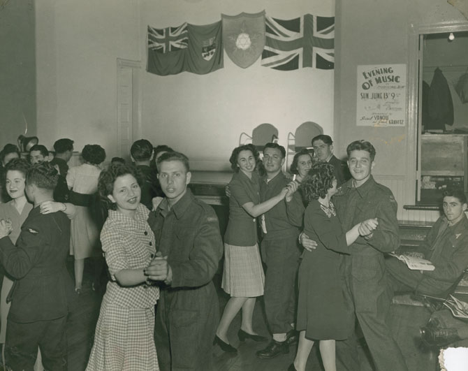 Evening of Music at the Quinpool Road Hostel-1942. 1940s Fashions & 1940s Hairstyles on display with servicemen in uniform in Halifax Nova Scotia. 