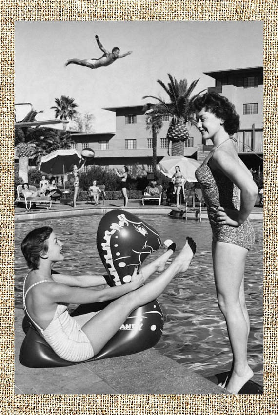 Vintage black and white photograph of two girls by the pool in 1950s swimsuits and 1950s hairstyles. Las Vegas, 1955