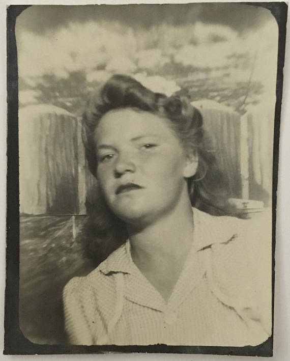 1940s vintage photobooth image of young teenage girl wearing a hair flower in her 1940s hairstyle