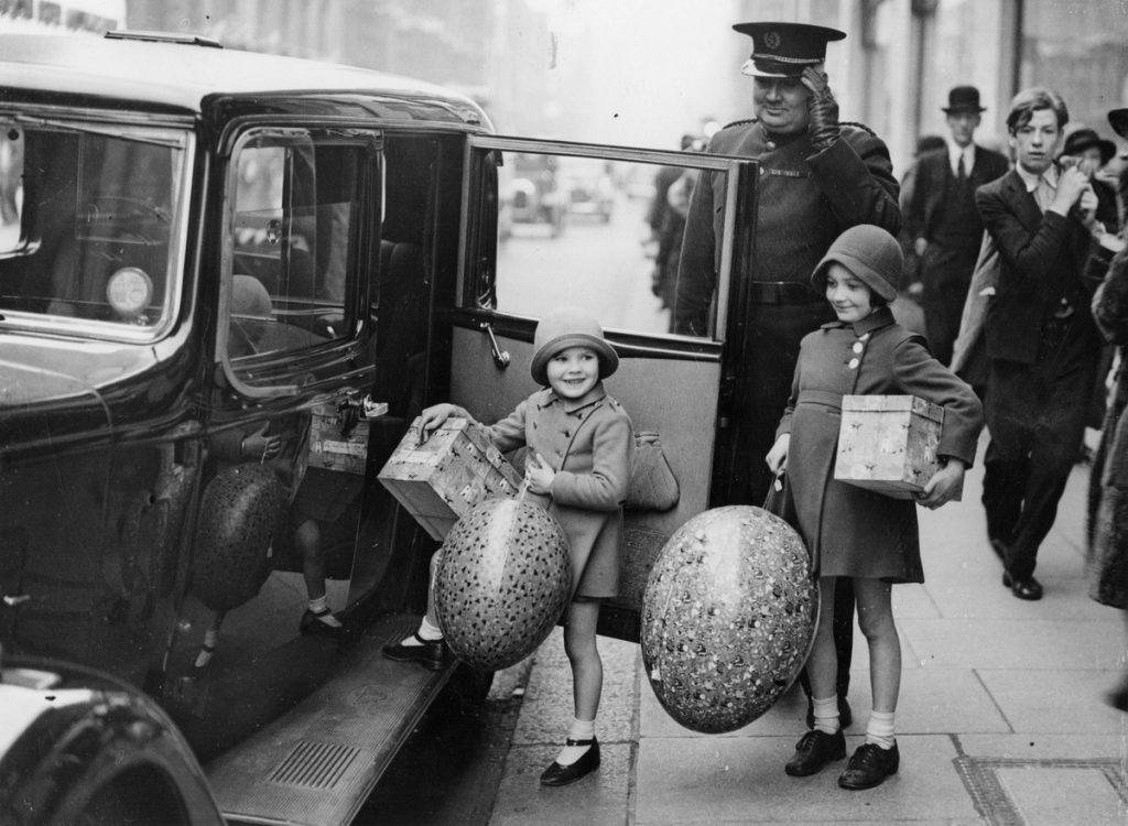 Easter Shopping in London 1936. Cute 1930s photo of a 2 young girls holding giant Easter eggs.