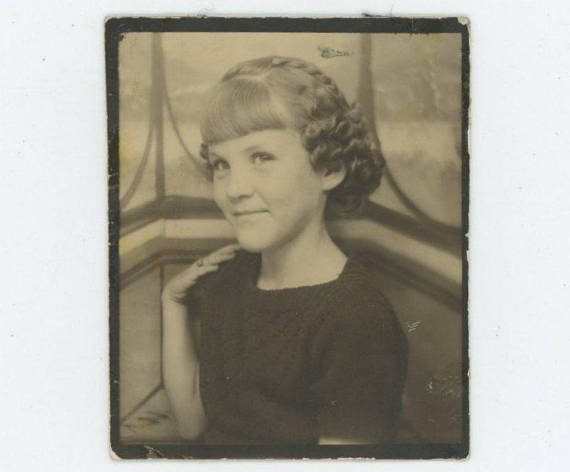 1930s photo 1940s photo of a young girl with milk maid braids posing in a photobooth. 