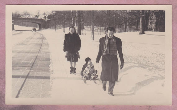 1940s vintage photo of a father pulling his kids on a sled in the winter time. 