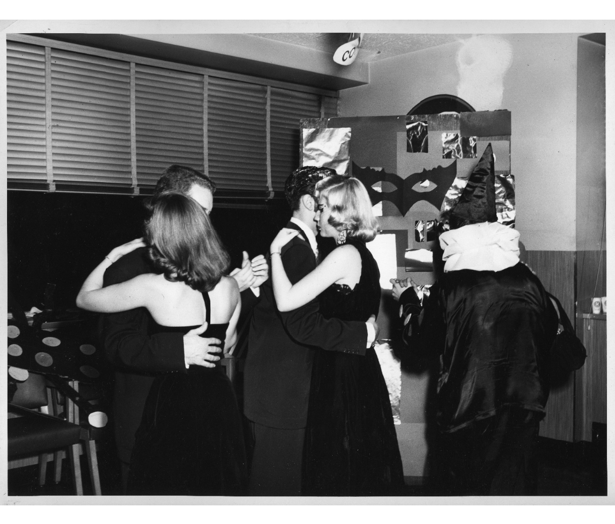 1950s vintage photo of a college Halloween dance featuring some in halloween costumes and the rest in 1950s eveningwear. 