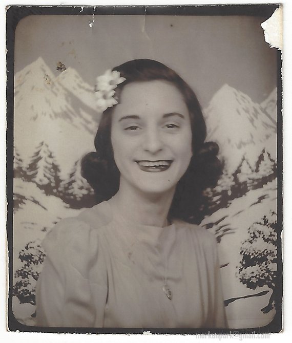 1940s photo of a young woman in a photo booth wearing a hair flower. Perfect 1940s vintage hairstyle inspiration. 