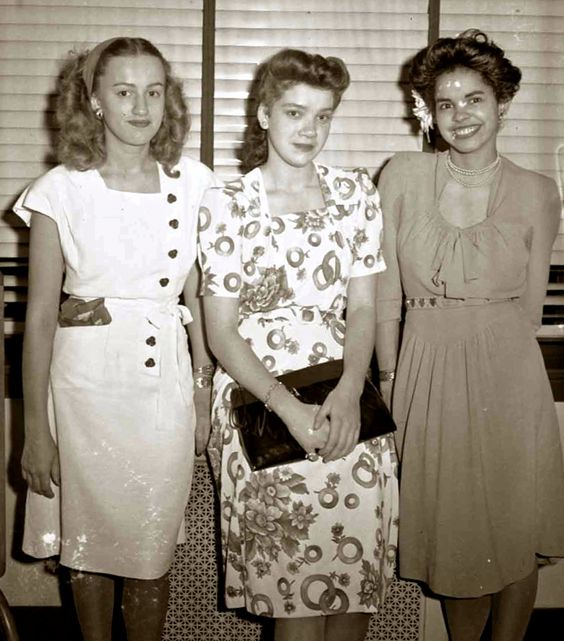 1945 of three young women in 1940s fashions and 1940s hairstyles posing for the camera. 