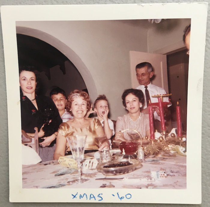 1960s vintage photo of a family smiling for the camera at their Christmas dinner. "Xmas 1960"