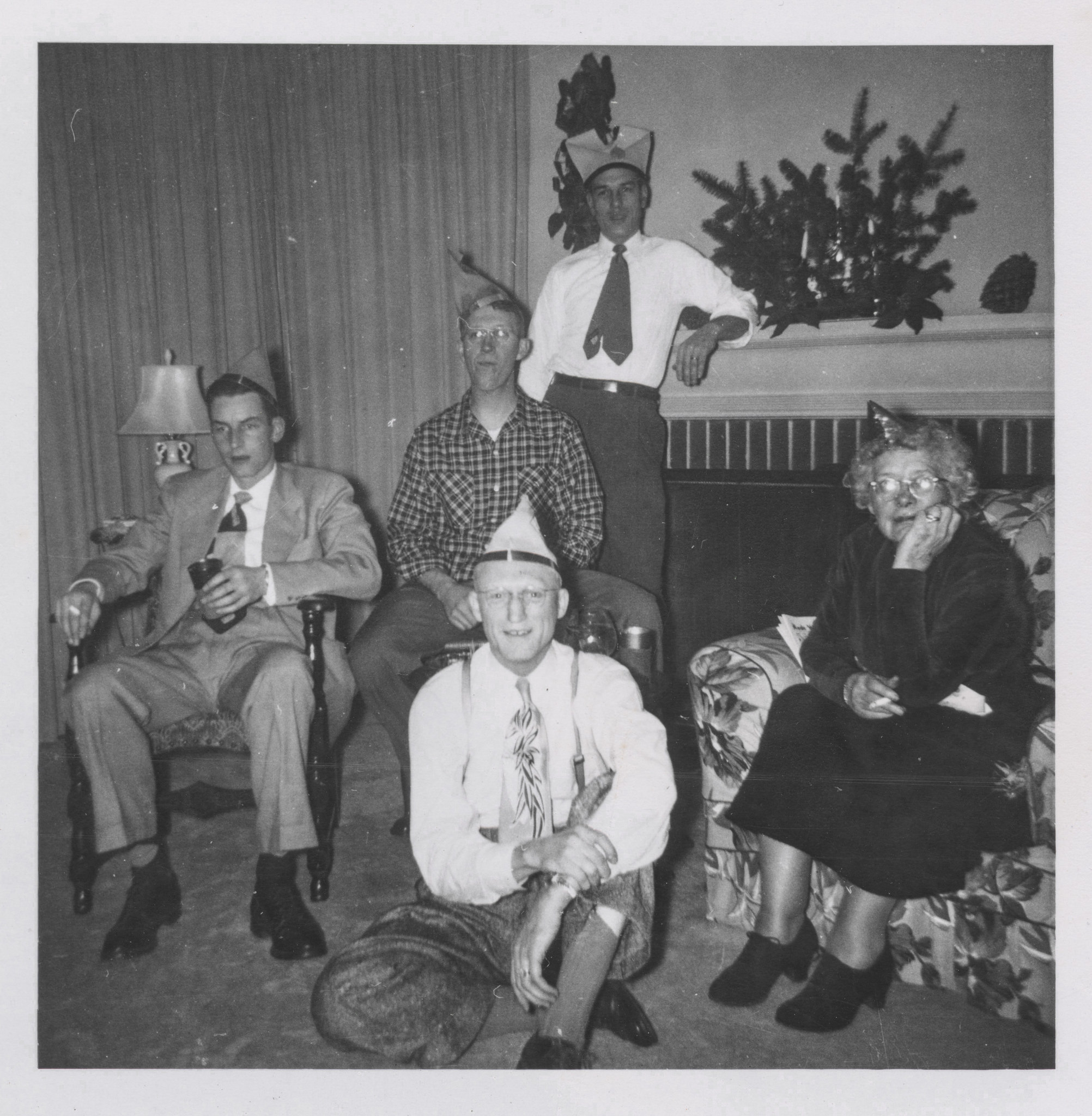 1950s vintage photo of a Fun family photo around the fireplace in their New Yers party hats. 