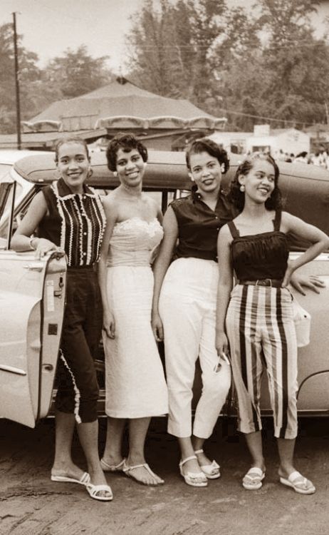 1950s vintage photo of four young Black Women in 1950s summer fashions / 1950s fashions posing together in front of a 1950s car. 