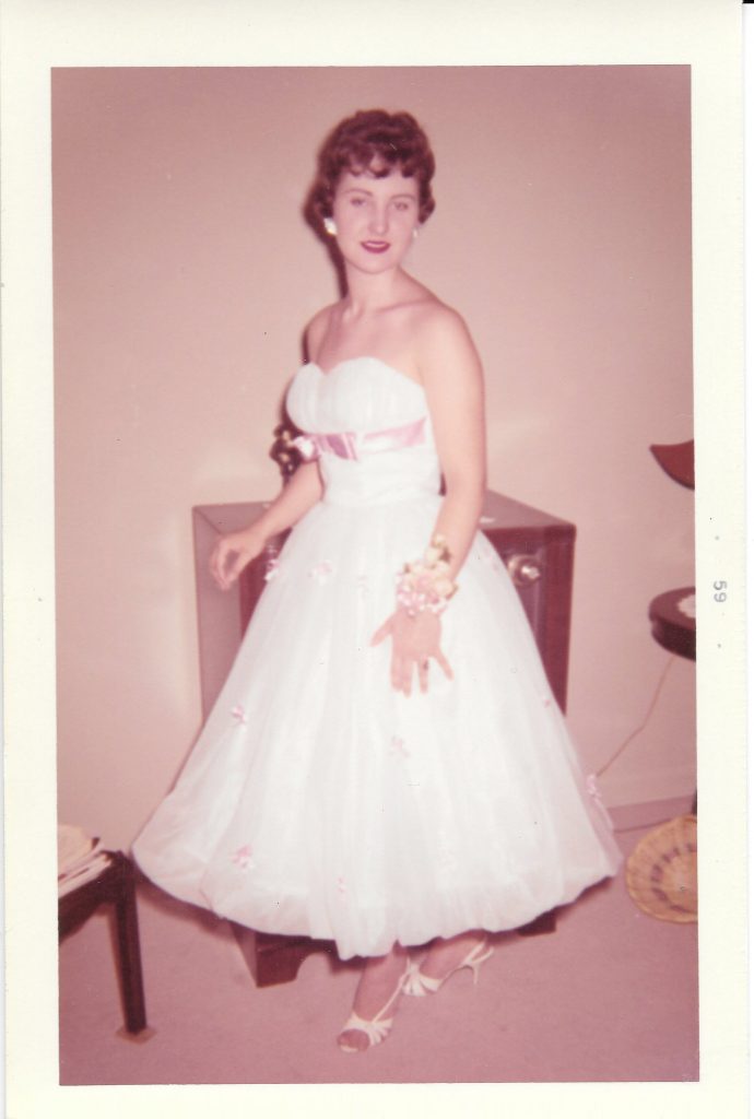 1959 vintage photo of a young woman in a 1950s formal dress in living room heading to a dance