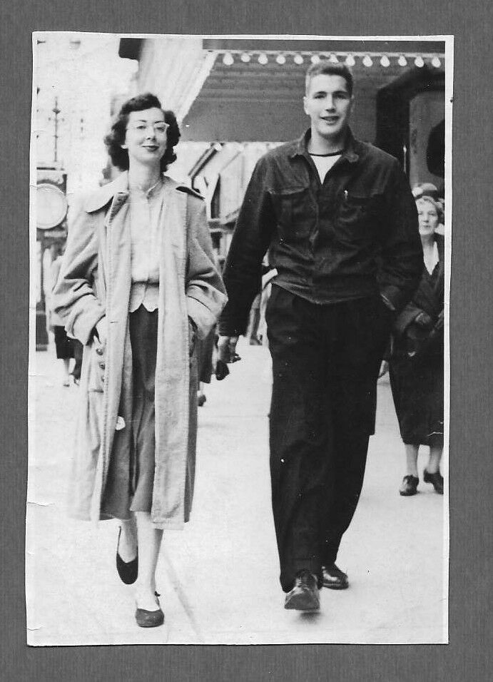 1950s vintage photo of a teenage couple in 1950s fashions walking down the street together. 