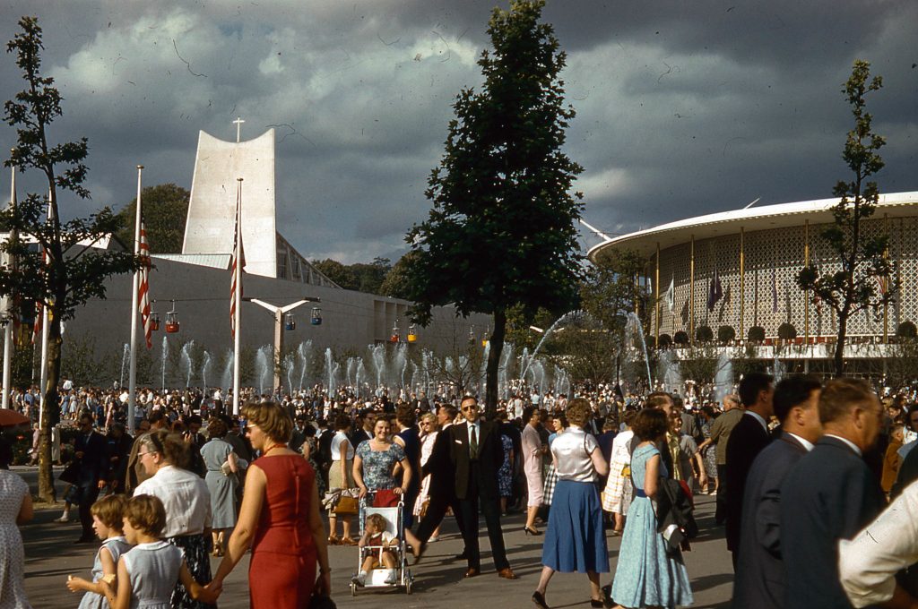 1950s vintage photo of people in 1950s fashions walking around the 1958 Brussels Worlds Fair. 