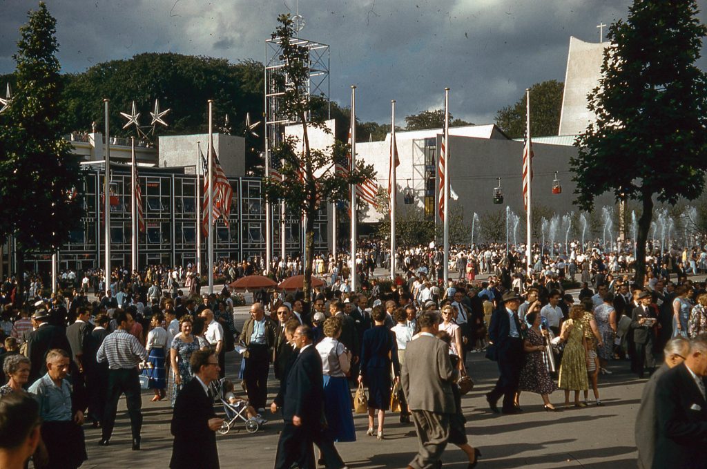 1950s vintage photo of people in 1950s fashions walking around the 1958 Brussels Worlds Fair. 