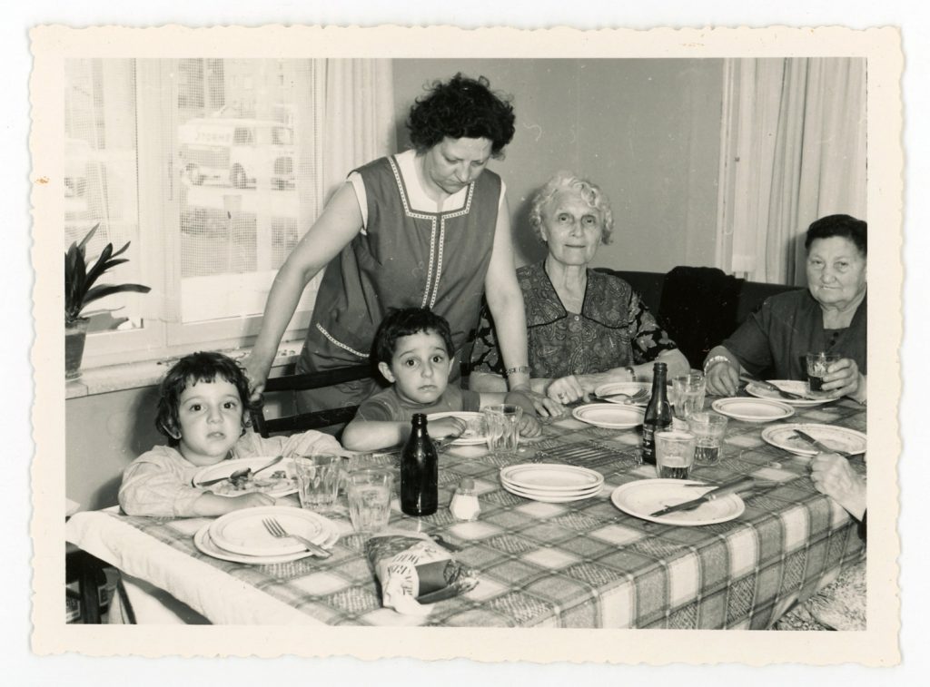 1960s Family Photo sitting around the kitchen table with kids, grandmother