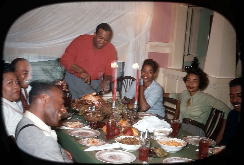 1960s vintage photo of a Black family in 1960s fashions enjoying Thanksgiving dinner together 