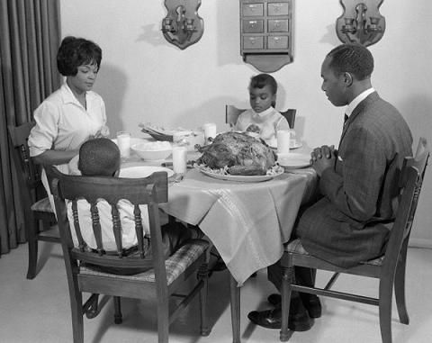 Black family / African American family sitting around the table about to enjoy thanksgiving turkey