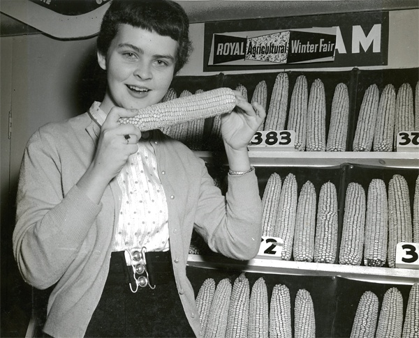 1950s photo of a young woman holding a corn on the cob at the Royal Winter Fair in Toronto.