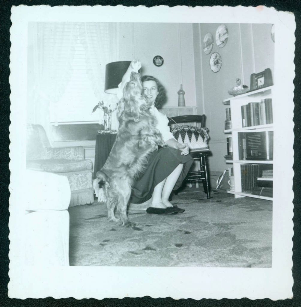 A woman holds up a treat for her spaniel dog. What a great look inside her living room (Late 1940s/ Early 1950s Photo). 