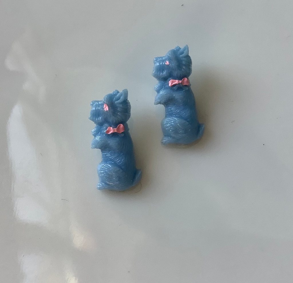 Tiny Scottie dog plastic button from the 50´s. Cute and charming blue dog with pink bow realistic button.