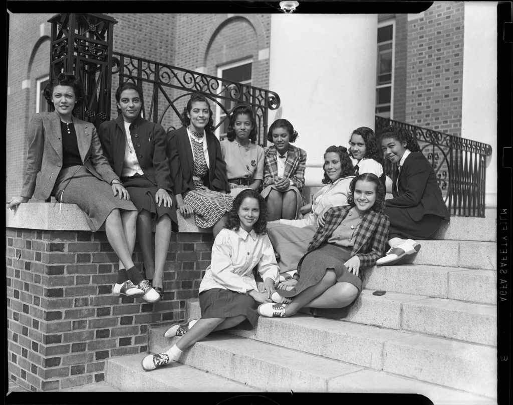 1939 photo by Charles “Teenie” Harris. Group portrait of ten Black women, including several wearing saddle shoes, gathered on steps of brick building