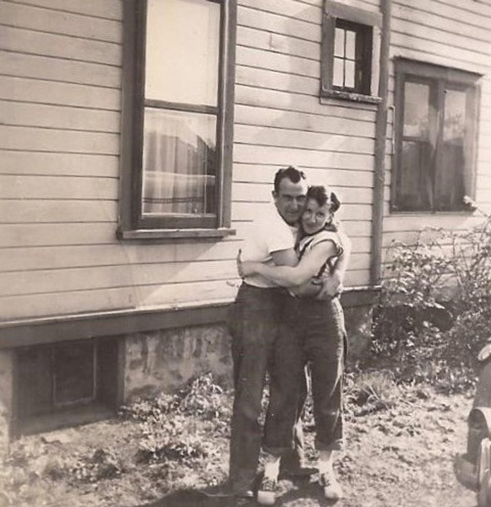 1940s vintage photo of a couple hugging in jeans and saddle shoes on the woman. Super 1940s fashion