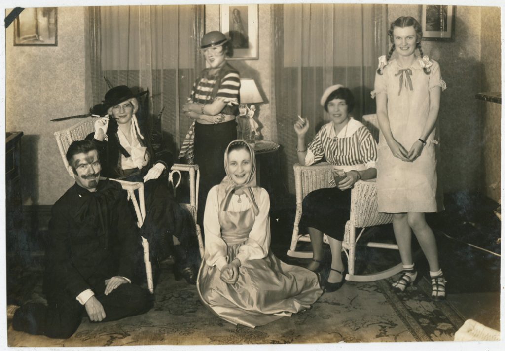 1940s vintage photo of a young adult Halloween party. Costume: Bonnie from Bonnie and Clyde. Possible a vampire, mime, old lady, a county lady and a young girl