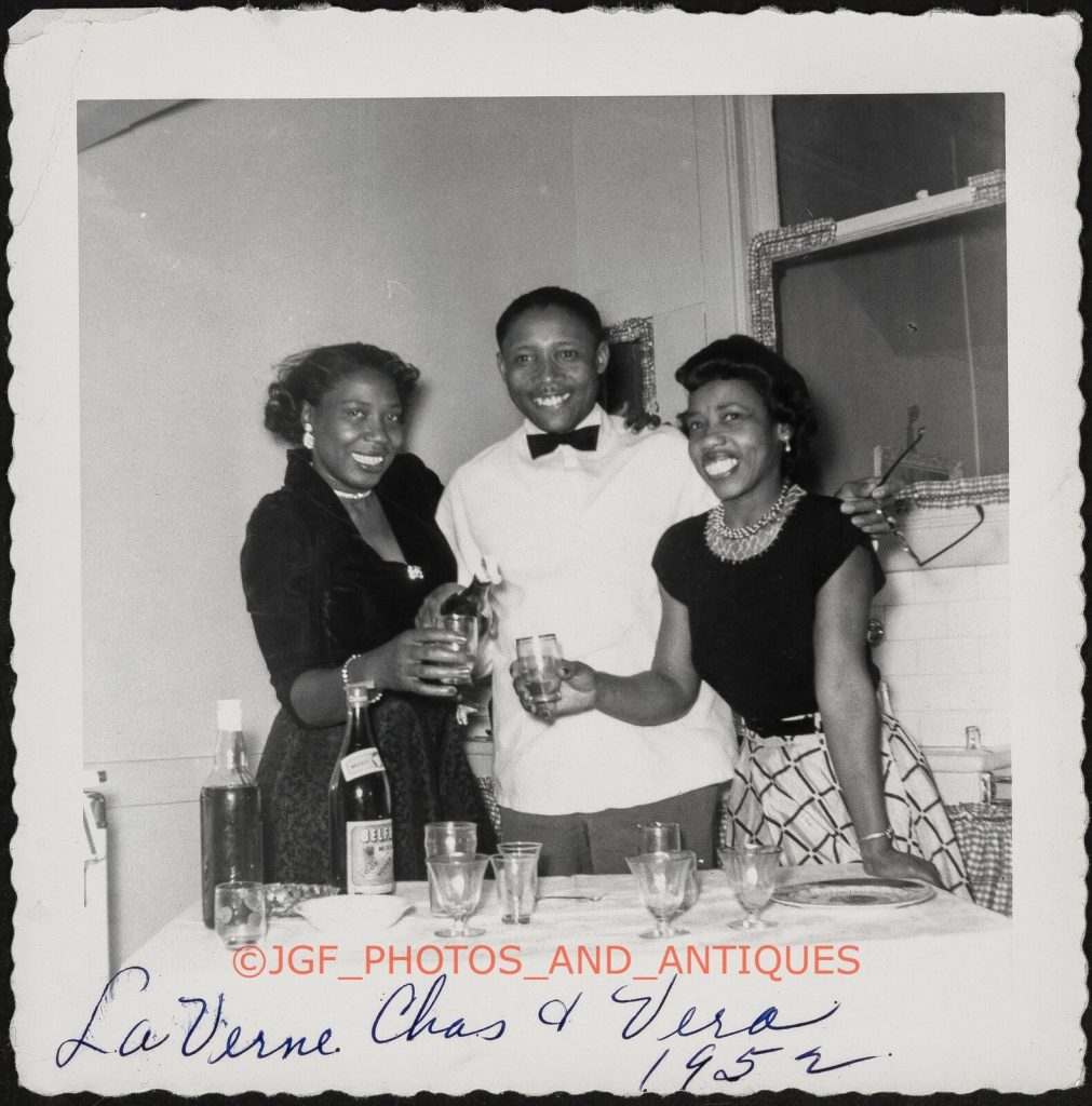 1950s Photo of friends enjoying a drink at a formal event. Fantastic 1950s Dresses on our stylish Black ladies. 