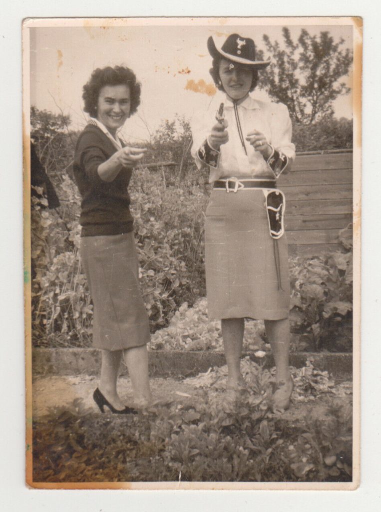 1950s vintage photo of a Cowgirl Halloween Outfit. Our lady in costume looks cute in her pencil skirt and simple white blouse (so does her friend). 