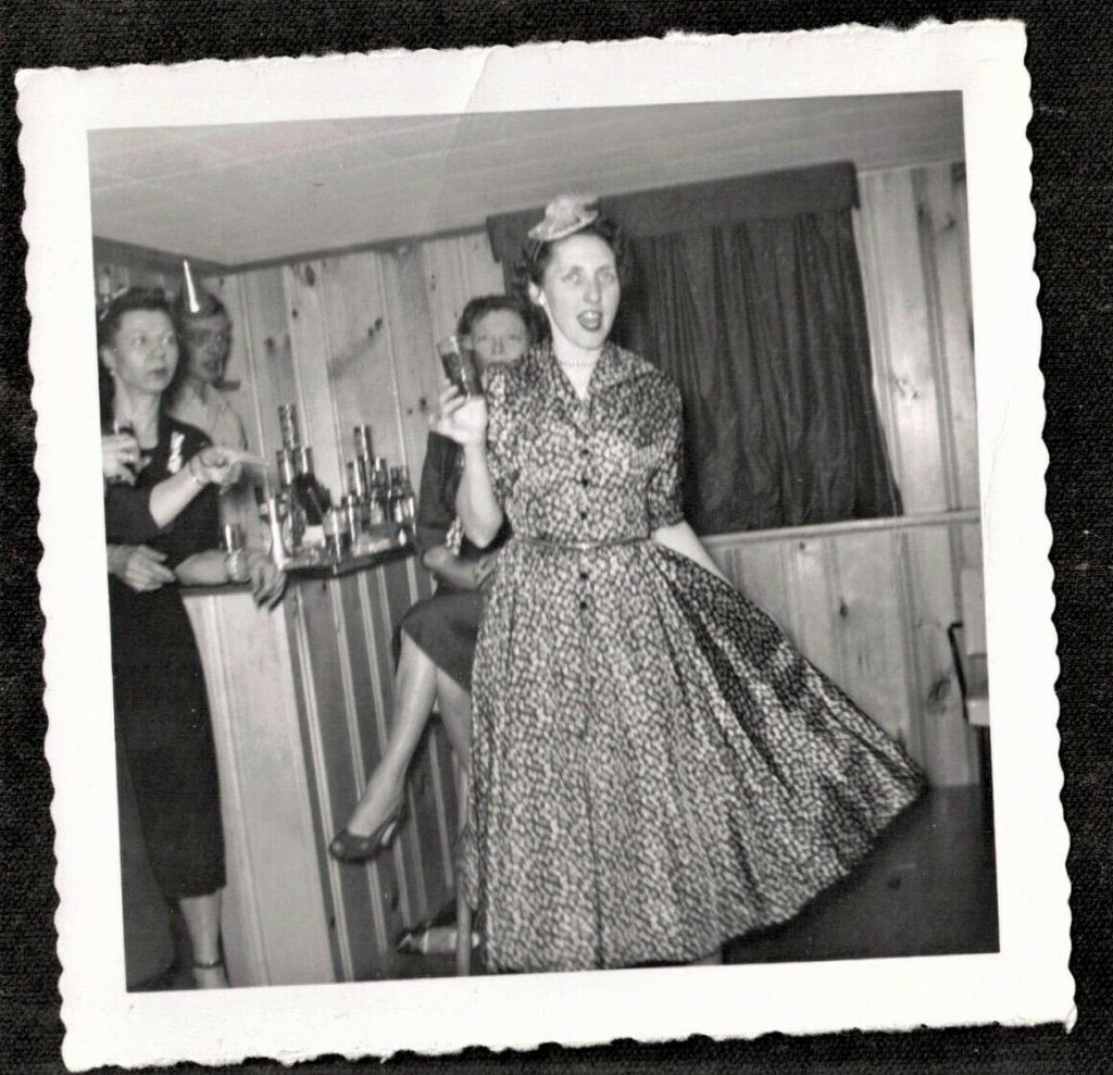 Fun vintage photo of People at Bar Enjoying Drinks - New Year's Eve. Late 1950s, early 1960s. Fun Mid century fashions. 