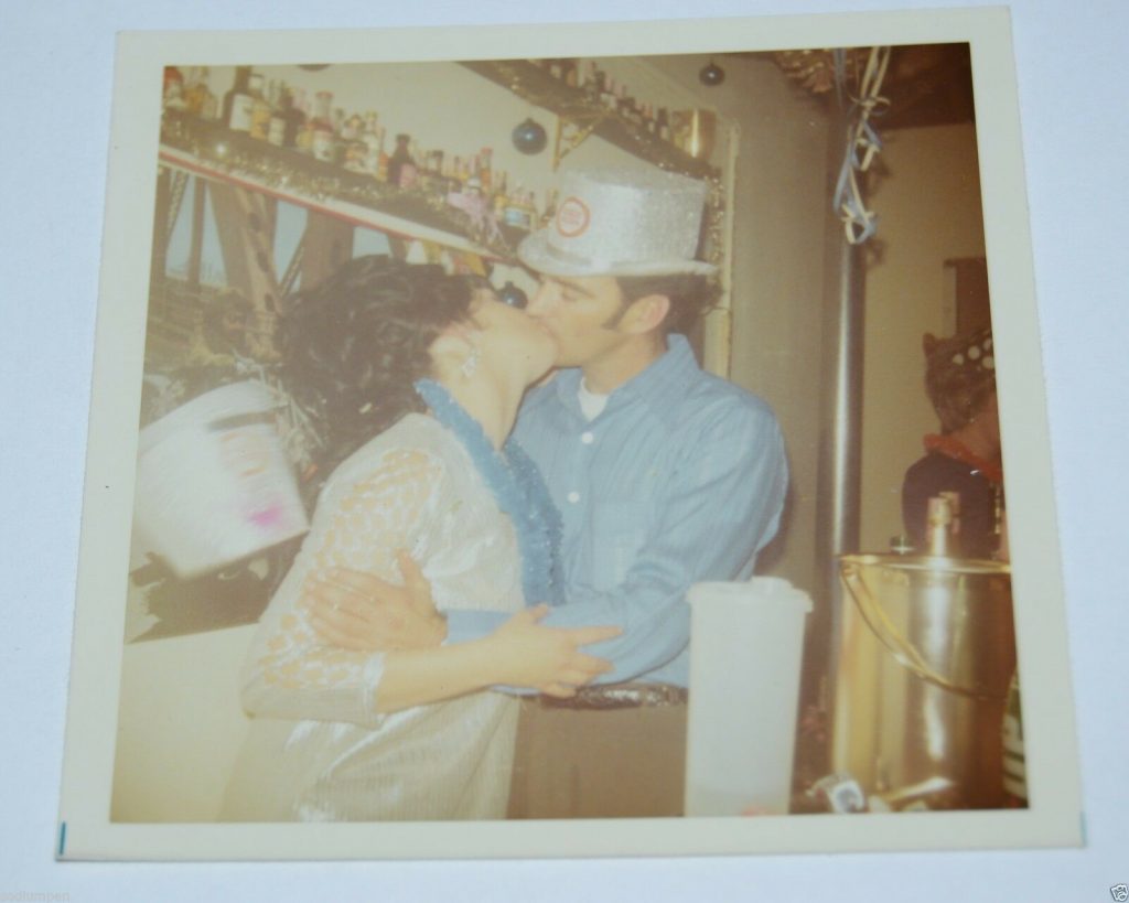 1960s vintage photo of a couple in 1960s fashions and 1960s hairstyles kissing at the bar