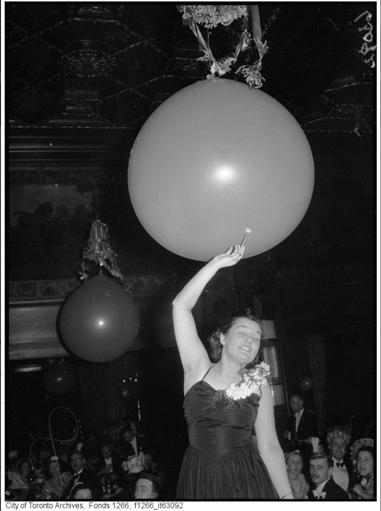 1939 New Years eve photo of a woman about to pop a balloon while wearing a 1930s dress