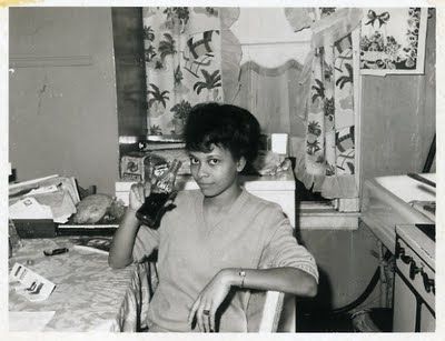 1950s / 1960s photo of a young Black woman taking a drink break at her kitchen table