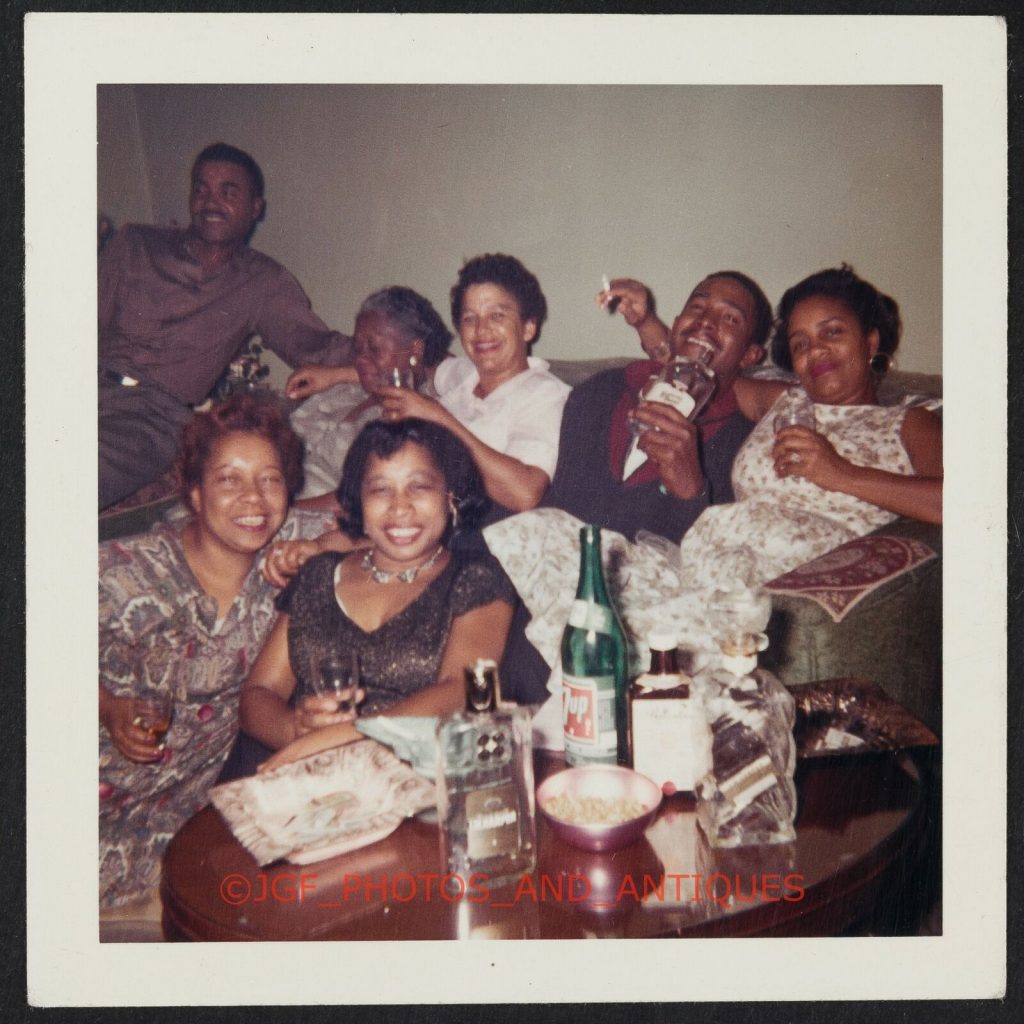 1960s vintage photo of a group of Black Men and Women having a cocktail party all dressed up in 1960s fashions.