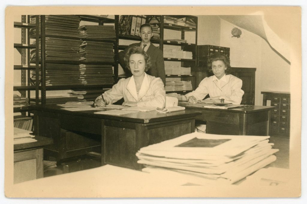 1950s vintage photo of two office women in a room filled with ledgers and paperwork