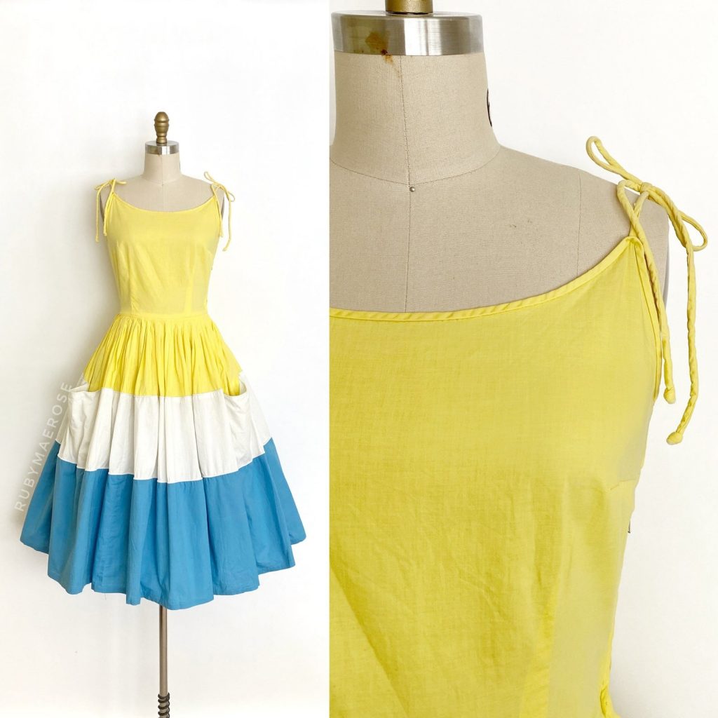 1950s Fashion: Glorious 1950’s cotton sun dress. This dress features a large scale colour block of yellow, white and blue, self tie straps and clever pocket placement. Fitted bodice with a scooped neckline, comfortable self tie spaghetti straps, nipped waist and a very full pleated skirt with two hidden pockets. Side metal zipper.